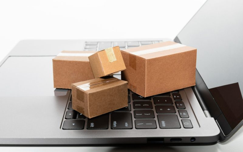 Imagem ilustrativa sobre o que é dropshipping mostrando pequenas caixas de mercadorias sobre o teclado de um computador, ilustrando como funciona o comércio online.